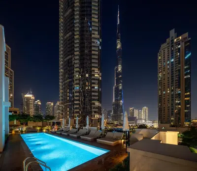 a rooftop pool with a view of a city at night at Peaceful Dunes 2 - Near Burj Khalifa & Dubai Mall in Dubai