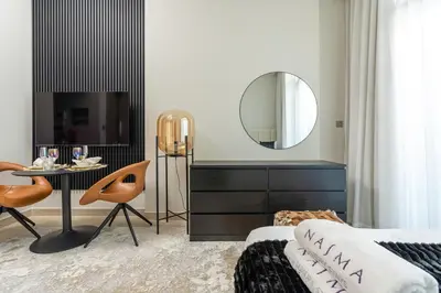 a bedroom with a bed and a mirror and a table at Nasma Luxury Stays - Azizi Riviera 6 Cozy Studio with Burj Khalifa View in Dubai