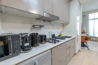 a kitchen with white cabinets and a counter top at Nasma Luxury Stays - Azizi Riviera 6 Cozy Studio with Burj Khalifa View in Dubai