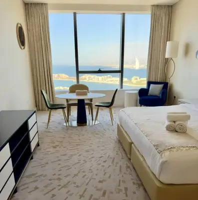 a hotel room with a bed and a table and chairs at Gorgeous Palm View in Dubai