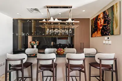 a dining room with a bar with chairs and a painting at Family Friendly luxurious Waterfront Apartment - By Dustay in Dubai