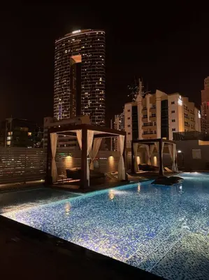 a large swimming pool with a city skyline at night at 5 Mins to JBR Beach, Luxury Studio in Dubai Marina's Best Tower in Dubai