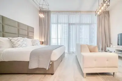 a bedroom with a large bed and a chair at 5 Mins to JBR Beach, Luxury Studio in Dubai Marina's Best Tower in Dubai