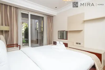 a white bedroom with a large bed and a tv at Mira Holiday Homes - Spacious 2 bedroom with patio in Palm Jumeirah in Dubai