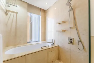 a bathroom with a tub and a shower with a window at HAVN - Studio Dubai Marina View in Dubai