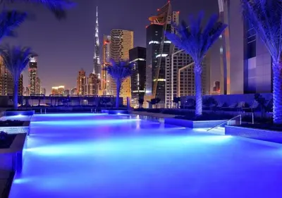 a city at night with blue lights and palm trees at HAVN - Studio Dubai Marina View in Dubai