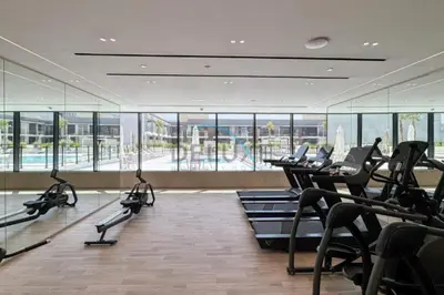 a gym with rows of treadmills and elliptical machines at Cozy 1BR at Binghatti Corner, Jumeirah Village Circle by Deluxe Holiday Homes in Dubai