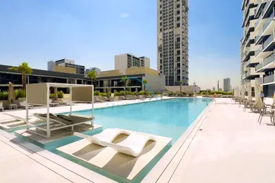 a swimming pool with lounge chairs on a building at Cozy 1BR at Binghatti Corner, Jumeirah Village Circle by Deluxe Holiday Homes in Dubai