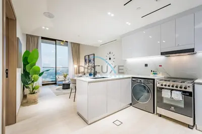 a kitchen with white cabinets and a washer and dryer at Cozy 1BR at Binghatti Corner, Jumeirah Village Circle by Deluxe Holiday Homes in Dubai