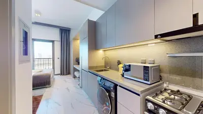 a kitchen with a stove and a microwave at Mag Eye 910 - Tranquil Studio Apartment in Meydan in Dubai