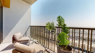 a balcony with a chair and two plants on it at Mag Eye 910 - Aesthetic Studio Apartment in Meydan in Dubai