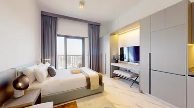 a bedroom with a bed and a desk and a television at Mag Eye 920 - Classy Studio Apartment in Meydan in Dubai