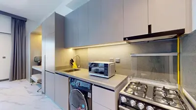 a kitchen with a washer and a stove and a microwave at Mag Eye 890 - Modern Studio Apartment in Meydan in Dubai