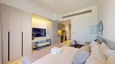 a bedroom with a white bed and a desk at Mag Eye 890 - Modern Studio Apartment in Meydan in Dubai