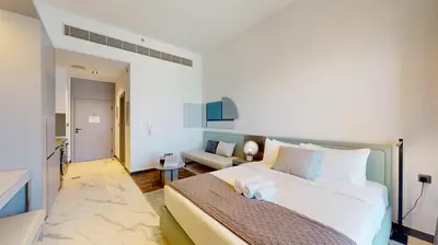 a bedroom with a large bed and a living room at Mag Eye 890 - Modern Studio Apartment in Meydan in Dubai