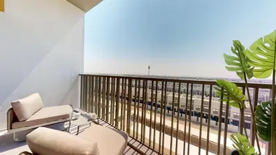 a room with a chair and a balcony with a view at Vacationer I Stylish Studio I Skyline & Community Views I 12 Mins to Downtown I MAG Eye 910 in Dubai