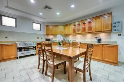 a large kitchen with a wooden table and chairs at Prestigious 5BR Villa with Assistant Room and Private Pool in Frond O Palm Jumeirah by Deluxe Holiday Homes in Dubai