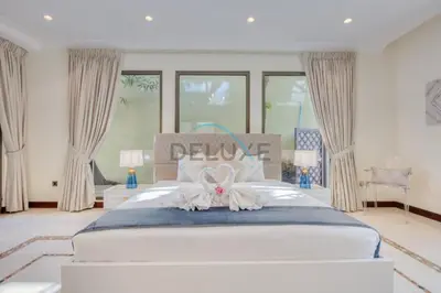 a bedroom with a white bed with a flower on it at Prestigious 5BR Villa with Assistant Room and Private Pool in Frond O Palm Jumeirah by Deluxe Holiday Homes in Dubai
