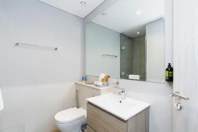 a bathroom with a sink and a toilet and a mirror at Citihome - 1BR with Huge Balcony & Easy Transport Access in Dubai