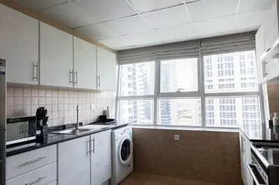 a white kitchen with a washer and dryer in it at Handsome 1BR in Armada Tower 3 in Dubai