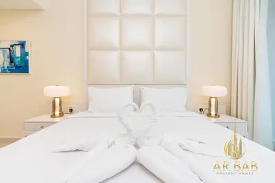 a white bed with white sheets and two lamps at Damac Maison Mall Street - Royal 3BR - Burj Khalifa View - Near Dubai Mall in Dubai