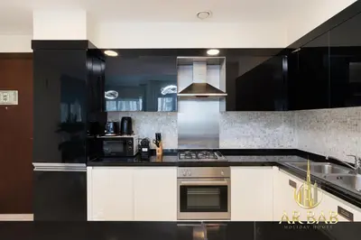 a kitchen with black and white cabinets and a stove at Damac Maison Mall Street - Royal 3BR - Burj Khalifa View - Near Dubai Mall in Dubai