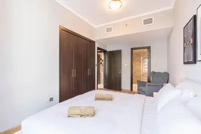 a bedroom with a large white bed and a chair at Cozy Home at the Heart of Marina on 52nd Floor in Dubai