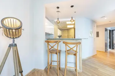a kitchen with two bar stools and a tripod at Cozy Home at the Heart of Marina on 52nd Floor in Dubai