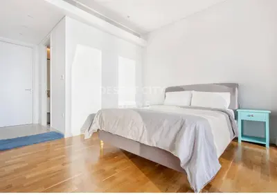 a white bedroom with a bed and a blue table at Luxurious 2 Bed in Bluewaters, Hosted by Desert City Stays in Dubai