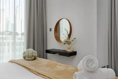 a bedroom with a bed with a mirror and towels at White Sage Sun and Sand 1BR at Beach Isle Emaar BeachFront in Dubai