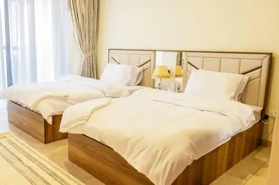 two beds with white sheets and pillows in a bedroom at Lux two br w Sea Views from rooms in Dubai Marina in Dubai