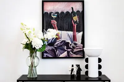 a vase of flowers on a table with a painting at Ultra-Chic 1BR Near Marina & Beach Walk in Dubai