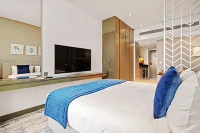 a bedroom with a large white bed and a flat screen tv at DAMAC MAISON PRIVE - Lake View in Dubai