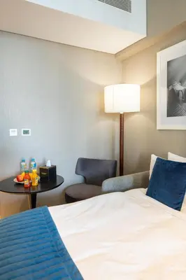 a hotel room with a bed and a chair and a table at DAMAC MAISON PRIVE - Lake View in Dubai