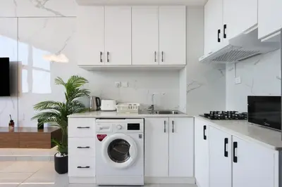 a white kitchen with a washing machine in it at Modern Studio in JVC, Near Parks and Highways in Dubai