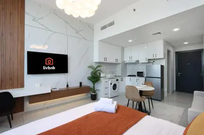 a bedroom with a bed and a kitchen with a tv at Modern Studio in JVC, Near Parks and Highways in Dubai