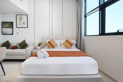 a white bedroom with a large bed with pillows at Modern Studio in JVC, Near Parks and Highways in Dubai