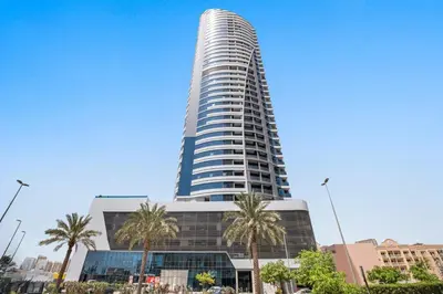 a tall building with palm trees in front of it at Modern Studio in JVC, Near Parks and Highways in Dubai