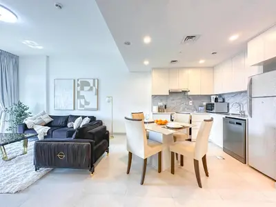 a kitchen and living room with a table and a couch at Ultra Luxury Flat with Amazing Pool Near to Burj in Dubai