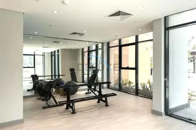 a gym with a treadmill and a mirror at Cozy Studio in Azizi Riviera 44, Al Merkadh by Deluxe Holiday Homes in Dubai