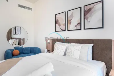 a bedroom with a bed and a blue chair at Cozy Studio in Azizi Riviera 44, Al Merkadh by Deluxe Holiday Homes in Dubai