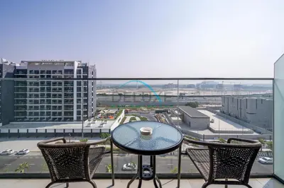 a table and chairs on a balcony with a view of a city at Cozy Studio in Azizi Riviera 44, Al Merkadh by Deluxe Holiday Homes in Dubai