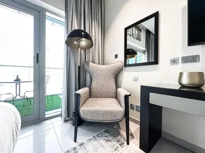 a bedroom with a chair and a desk with a mirror at Trophy Stays - Supreme Opulence - Chic Studio in Business Bay in Dubai