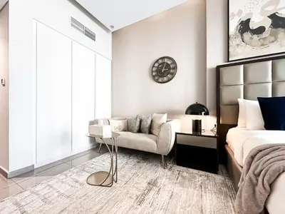 a bedroom with a bed and a couch and a clock at Trophy Stays - Supreme Opulence - Chic Studio in Business Bay in Dubai