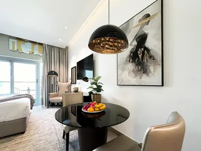 a living room with a table and a bedroom at Trophy Stays - Supreme Opulence - Chic Studio in Business Bay in Dubai