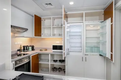 a kitchen with white cabinets and an open refrigerator at Burj Khalifa Views - 5 min walk from Dubai Mall - Upgraded - Designer Choice - 8 people - Dubai Opera in Dubai
