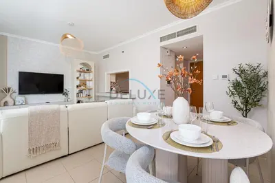 a white dining room with a table and chairs at Chic Studio in Burj Views Podium, Downtown Dubai by Deluxe Holiday Homes in Dubai