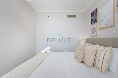 a white bedroom with a bed with a welcome sign on the wall at Chic Studio in Burj Views Podium, Downtown Dubai by Deluxe Holiday Homes in Dubai
