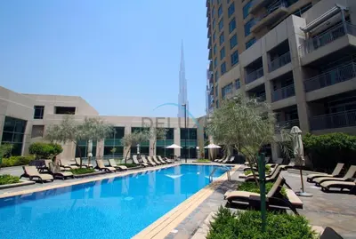 a swimming pool with lounge chairs and a building at Chic Studio in Burj Views Podium, Downtown Dubai by Deluxe Holiday Homes in Dubai