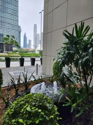 a garden with plants and a fountain in front of a building at Lovely Studio in Damac Maison Cour Jardin Business Bay in Dubai